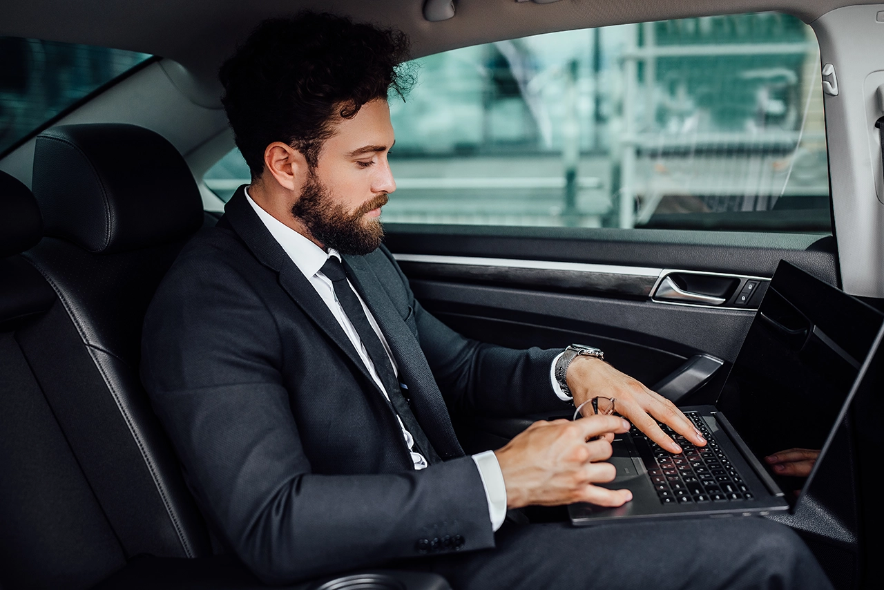 Businessman Working on Laptop in Luxury Car